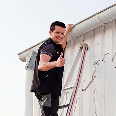 Guy on a ladder repairing a seamless gutter.