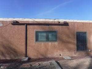 From our photo portfolio. Brown seamless gutter with downspout above a window on a flat roof house.